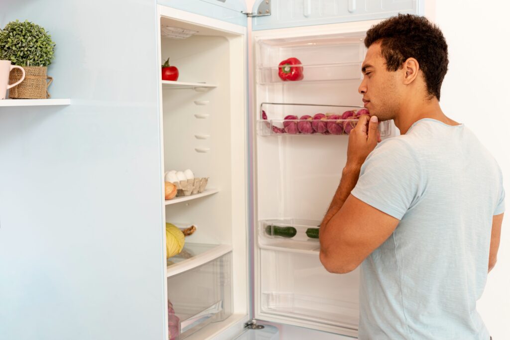 Close-up of a person wiping refrigerator door seals with a toothbrush and vinegar solution.