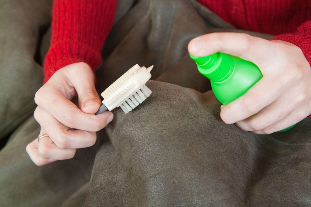Person wiping a leather couch using a soft microfiber cloth and natural cleaner