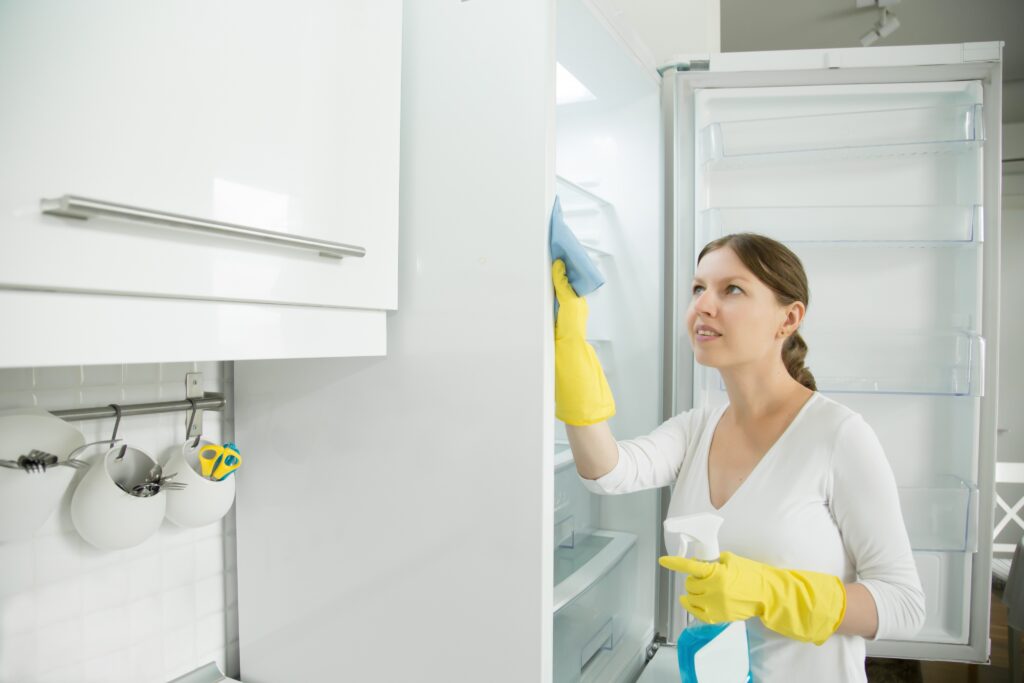 Person unplugging and removing groceries from a refrigerator before deep cleaning