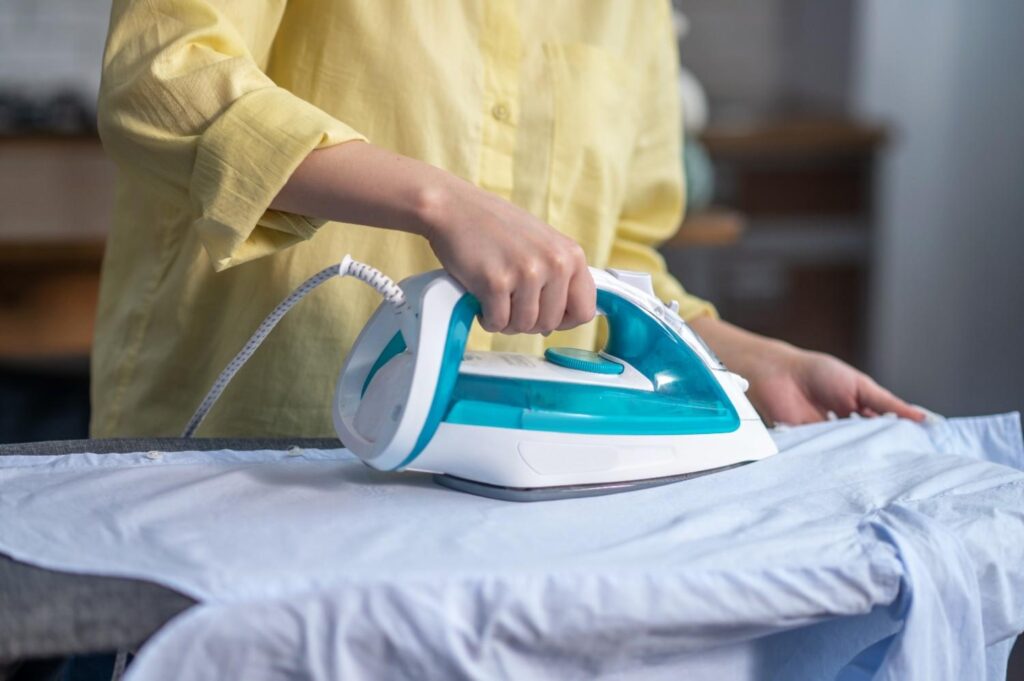Close-up of hands steaming a dress with a portable garment steamer